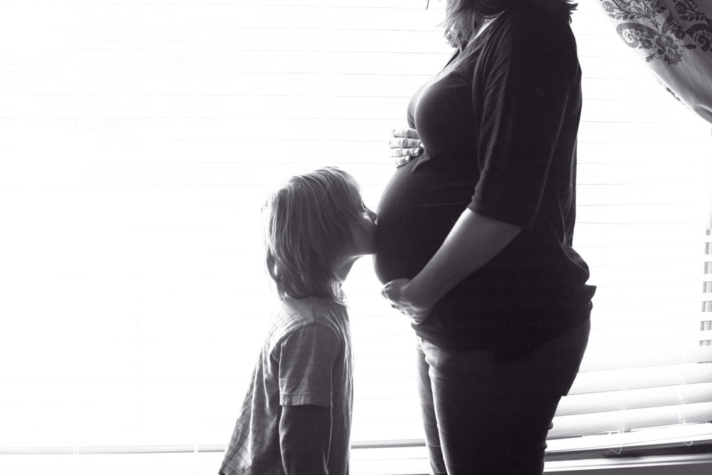 child kissing pregnant belly